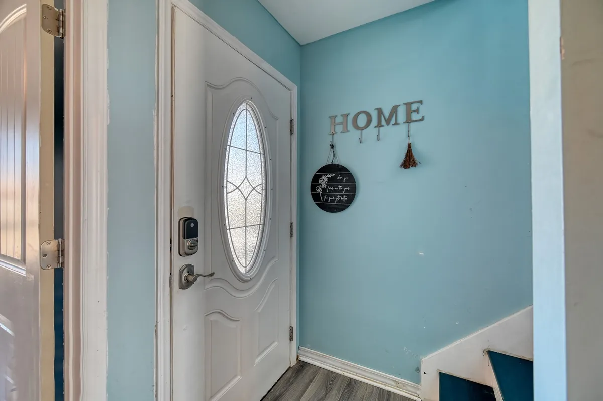 This image shows the front door area with a welcoming 'HOME' sign, a staircase, and a bright, inviting entryway. The space feels open and ready to greet guests, setting the tone for the retreat experience and hinting at the home's multi-level layout.